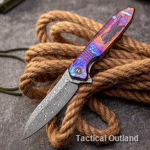 Damascus survival folding knife resting on rope