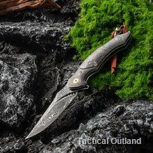 VG10 Damascus outdoor folding knife on dark rock and moss