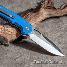 Blue VG10 folding knife opened on textured outdoor wood
