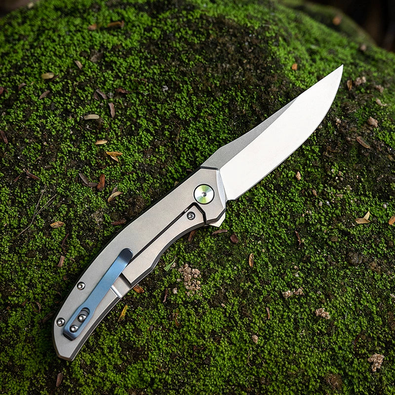 M390 outdoor folding utility knife on a mossy field background